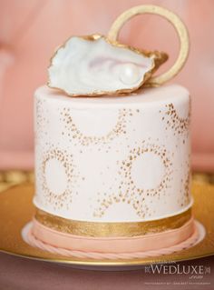 a white and gold wedding cake with a shell on top