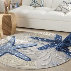 a living room with a white couch and blue starfish rugs on the floor