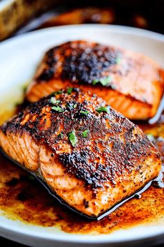 two salmon fillets on a white plate with brown sauce and garnishes