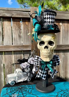 a skull wearing a top hat and bow tie sitting on a table next to a fence