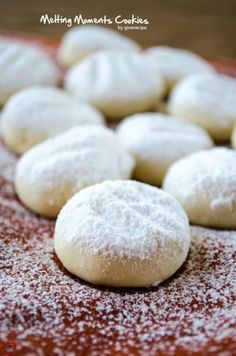 powdered sugar cookies are arranged on a red platter and ready to be eaten