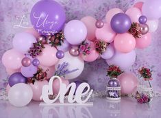 balloons and flowers are on display in front of a backdrop with the word, one