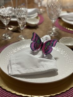 a table set with white plates and silverware, butterfly napkins on the plate