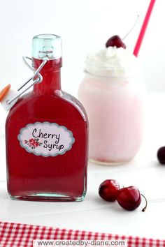 a bottle of cherry syrup next to a jar of whipped cream and some cherries