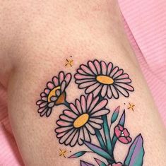 a close up of a tattoo with flowers on the side of a woman's thigh