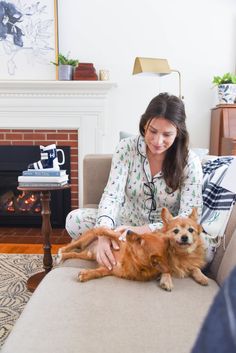 a woman sitting on a couch petting a dog