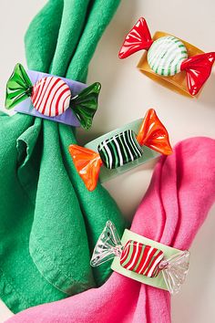 three candy candies wrapped in green and pink paper next to each other on a white surface