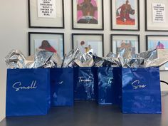 three blue shopping bags sitting on top of a table next to pictures and framed photos