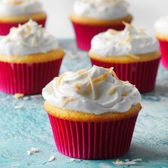 cupcakes with white frosting and sprinkles on a blue surface