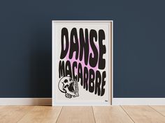 a framed poster with the words dance macabre on it in front of a blue wall