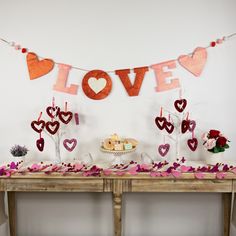 a table topped with lots of valentine's day decorations next to a sign that says love