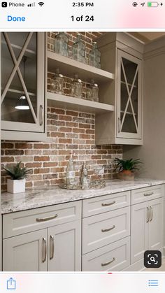 a kitchen with white cabinets and brick wall