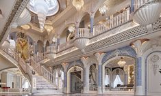 an elaborately decorated room with stairs and chandeliers on the ceiling, along with marble flooring