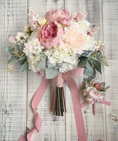 a bridal bouquet with pink and white flowers on a wooden background, tied to a ribbon