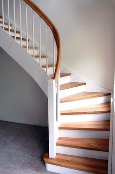 a white staircase with wooden handrails and tile flooring