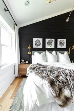 a bedroom with black walls and white bedding, two pictures on the wall above the bed