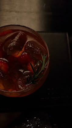 a drink in a glass with ice and garnish on the rim, sitting on a table