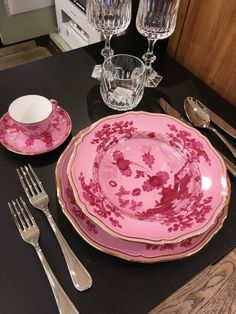 a pink china dinner set on a black table