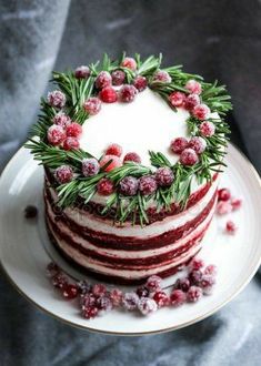 a three layer cake with cranberry frosting and fresh greenery on top