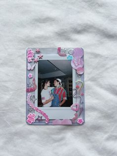 two people standing in front of a white sheet with pink flowers and butterflies on it