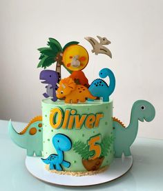 a dinosaur themed birthday cake with fondant topper and decorations on the bottom tier