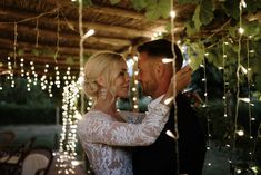 a bride and groom are kissing under the lights