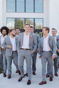 a group of men standing next to each other in front of a tall white building