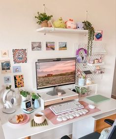 a desk with a computer on top of it and various pictures hanging above the keyboard