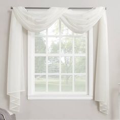 a window with white sheer curtains hanging from it's side