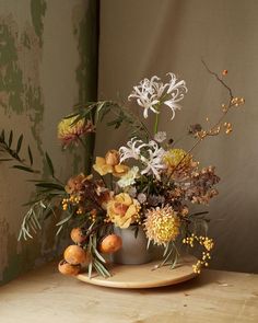 an arrangement of flowers in a vase on a plate