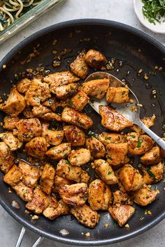 a skillet filled with chicken and garnished with parsley on the side