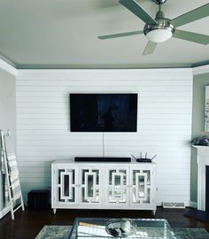 a flat screen tv mounted to the side of a white wall in a living room