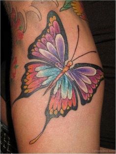 a colorful butterfly tattoo on the thigh