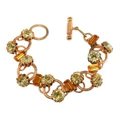 This is part of Chairish’s Costume Jewelry assortment.  Vintage bracelet embellished with beautifully faceted yellow rhinestones with amber colored accents. Interesting ring setting is gold plated. Unmarked. We believe this piece dates to the 1950s / 1960s era. Although it measures 8" in total, it fits like a 7" bracelet due to the toggle clasp. Measures about 1" wide. Condition is excellent for this type of vintage jewelry with only minor wear to the gold plating. Vintage Orange Metal Jewelry, Retro Jeweled Gold Jewelry, Antique Gold Crystal Jewelry, Retro Gold Jeweled Jewelry, Antique Gold Citrine Jewelry, Antique Citrine Gold Jewelry, Gold Jewelry With Jewels For Vintage Events, Vintage Orange Citrine Jewelry, Adjustable Gold Citrine Crystal Bracelet