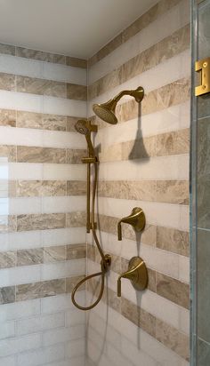 a shower head and hand shower in a bathroom with marble tiles on the back wall