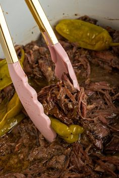 two spatulas are being used to stir beef and peppers in a pot with sauce