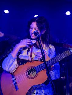 a woman playing an acoustic guitar on stage