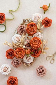 an arrangement of flowers on a plate with scissors and other items around it, including paper flowers