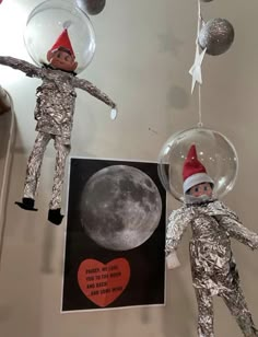 two elfs are hanging from the ceiling in front of a card that says i love you to the moon and back