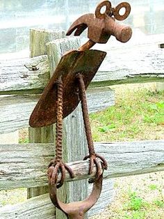 a metal bird hanging on a wooden fence