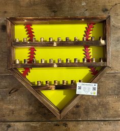 a wooden shelf filled with lots of candles on top of a yellow wall next to a sign