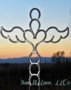 a metal sculpture in the shape of an angel's wings with sunset behind it