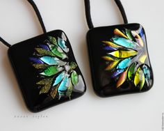 two black square pendants with colorful feathers on them