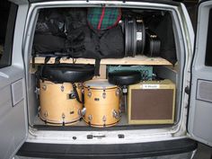 the back end of a van filled with musical instruments and gear, including drums and amps