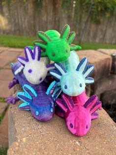 several different colored toy animals sitting on top of a rock