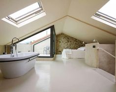 an attic bathroom with skylights and white fixtures