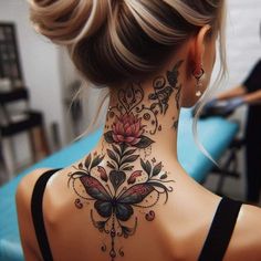 a woman's back neck tattoo with flowers and butterflies on the upper part of her neck