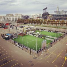 an aerial view of a tennis court in the middle of a parking lot with buildings in the background