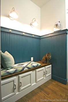 a cat sitting on top of a wooden bench in a room with blue paneling