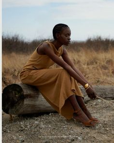 a woman sitting on top of a wooden log